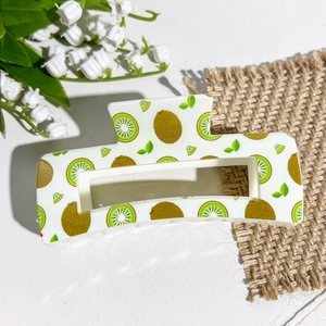 Détail d'une pince à cheveux carrée avec imprimés réalistes de kiwi et motifs de feuilles