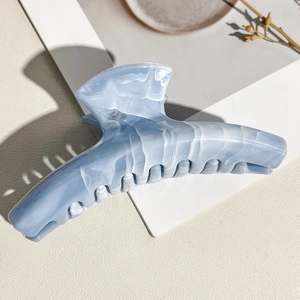Detailed macro view of the curved marble hair claw clip with sky blue acetate texture