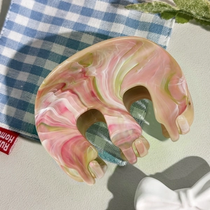 Vue détaillée de la grande pince à cheveux marbrée rose et verte avec bords ondulés