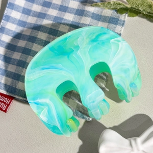 Détail d'une pince à cheveux en marbre en forme de M, tons vert menthe et bleu clair