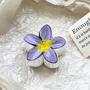 Detailed macro view of purple plumeria flower hair claw clip with yellow center detail