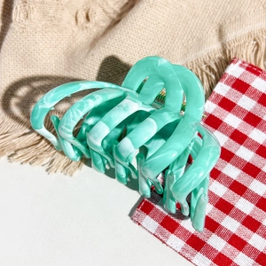 Close-up detail of mint green marble texture and multi-tooth design on hair claw clip