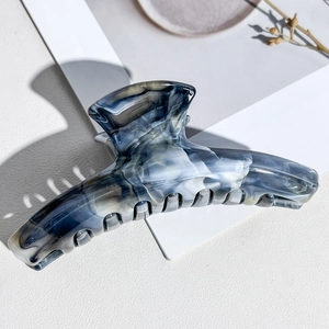 Macro detail of large curved marble pattern hair claw clip with acetate texture