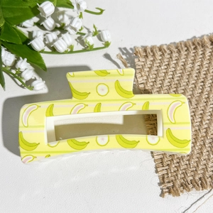 Détail de la pince à cheveux carrée avec imprimé banane et carambole sur jaune