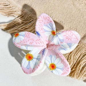 Close-up of pink frangipani hair claw clip with white daisy print on beige linen fabric