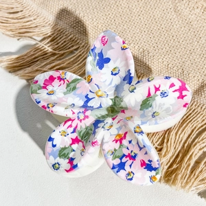 Macro shot of floral plumeria hair claw clip with colorful UV printed patterns