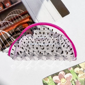 Détail d'une grande pince à cheveux en acrylique au design de fruit du dragon rose et blanc