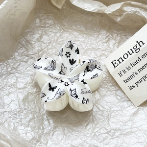 Macro view of white floral hair claw with butterfly print and Sweet text detail