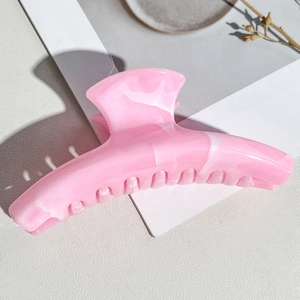 Detail of pink marble pattern hair claw clip with smooth acetate finish and spring mechanism