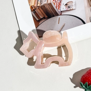 Close-up of translucent pink puppy-shaped hair claw clip with smooth acrylic finish