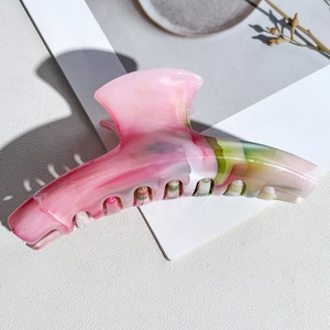 Macro detail of curved marble hair claw clip with pink and green patterns