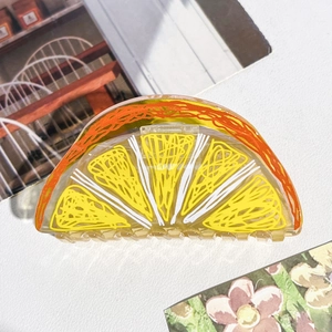 Détail d'une grande pince à cheveux en acrylique avec un design de tranche d'orange vive