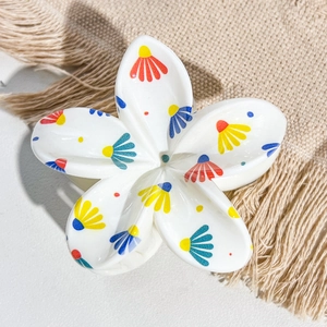 Detail of white plumeria hair claw clip with colorful floral UV print on woven textile
