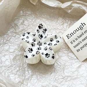 Detail view of flower hair claw clip with cat paw prints on white acetate material