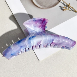 Close-up of a large marble texture hair claw clip in purple and blue acetate patterns