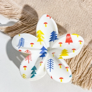 Close-up of frangipani hair claw clip with colorful UV printed Christmas trees and mushrooms