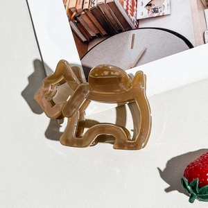 Detailed view of brown dog-shaped acetate hair claw clip on a minimalist aesthetic background