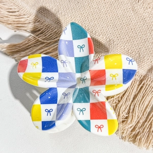 Detailed top view of a colorful checkerboard flower hair claw with small bow patterns