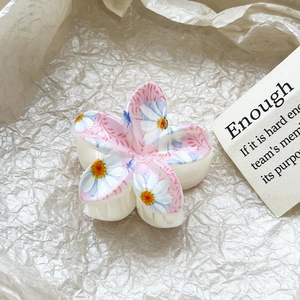 Detail view of tropical plumeria hair claw clip with floral patterns on beige paper