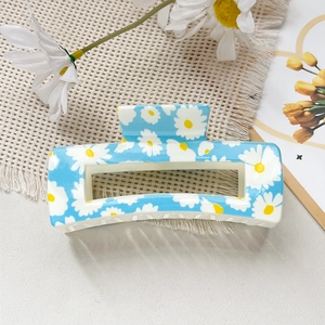 Vue détaillée d'une pince à cheveux carrée bleue avec motif marguerites sur tissu