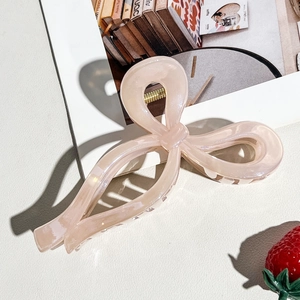 Detailed view of the large pearlescent pink bow hair claw clip with golden metal spring