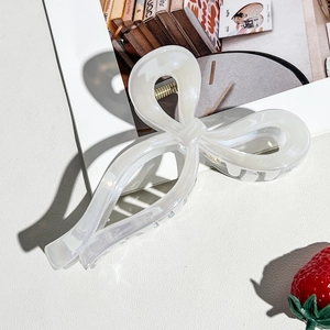 Macro detail of elegant pearlescent white bow claw clip on a stylish textured background
