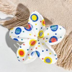 Detailed macro view of plumeria hair claw clip with colorful polka dots on woven fabric