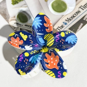 Detailed view of dark blue plumeria hair claw with colorful pop art graffiti patterns