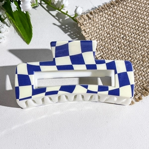 Close-up of blue and white checkered rectangular hair claw clip on textured background