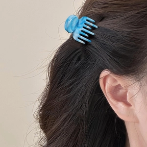 Blue marble resin hair claw clip for women shown on dark hair with sleek seven-tooth design