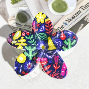 Detailed view of colorful floral UV printed resin hair claw on a white textured surface