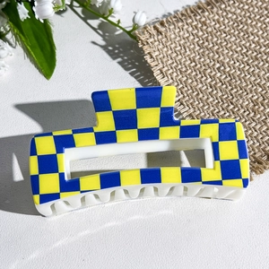 Macro detail of square hair claw clip featuring yellow and blue checkerboard pattern design