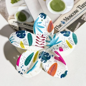 Detail of white flower hair claw with colorful tropical palm leaves and monstera prints