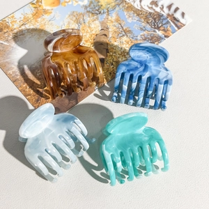 Macro shot of marble textured flower hair claws in amber, blue, grey, and green colors