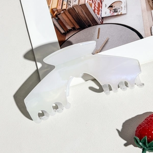 Detail of large pearlescent white acrylic claw clip showing its glossy iridescent texture