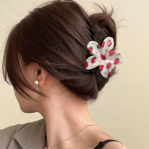 Floral claw clip with red strawberry print worn on a brunette bun for a cute styling