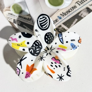 Macro detail of white flower hair claw clip with colorful artistic graffiti pattern