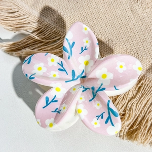 Detail shot of a pink floral hair claw clip with white daisy print on soft beige fabric