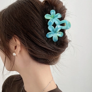 Blue marble floral hair claw clip securing a bun on model with elegant jewelry