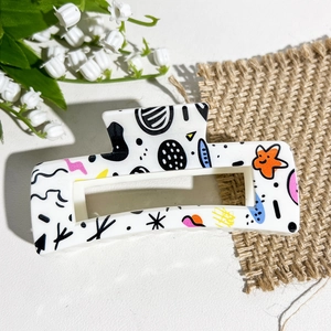 Détail d'une pince à cheveux carrée avec motifs graffiti colorés et sourires joyeux