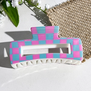 Detail of a rectangular hair claw clip with pink and blue checkerboard pattern