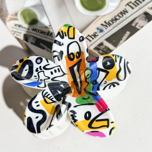 Macro detail of a flower hair claw clip with colorful abstract graffiti patterns on white
