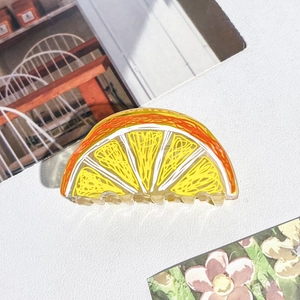 Détail d'une grande pince à cheveux en acrylique motif orange sur fond esthétique