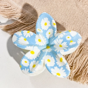 Close-up of blue floral hair claw clip with white daisy print and glossy finish