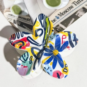 Detail showing the colorful graffiti floral pattern on a white resin hair claw clip