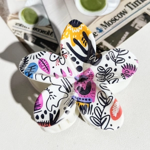 Close-up of a floral hair claw with colorful graffiti patterns on a white background