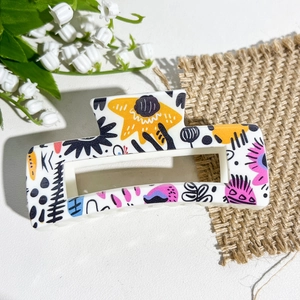 Gros plan sur la pince à cheveux carrée avec motifs floraux sur résine blanche