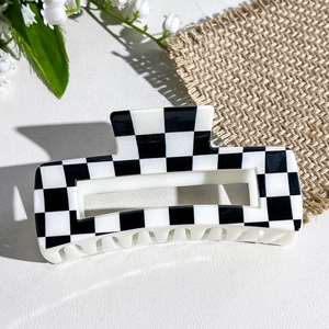 Close-up of a square black and white checkerboard hair claw clip with smooth resin finish