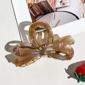 Detailed close-up of amber translucent bow hair claw with elegant aurora glitter finish
