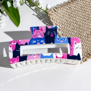 Detail of rectangular hair claw clip with colorful cartoon cat print and white teeth